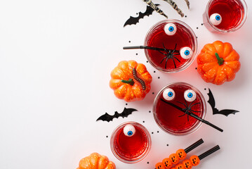 Halloween concept. Top view photo of floating eyeball punch in glasses cocktail straws spiders skeleton hand pumpkins bat silhouettes centipede and confetti on isolated white background with copyspace