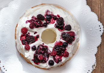 Angel Food Cake on white board sliced and filled with whipping cream, topped with summer berries, top view