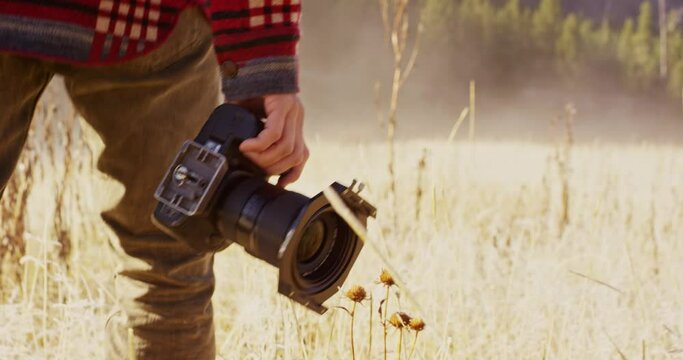Man walking and taking photos in grass field in Yellowstone National Park