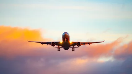 Rolgordijnen Het silhouet van een passagiersvliegtuig dat binnenkomt om te landen tegen de achtergrond van de avondrood. © fifg