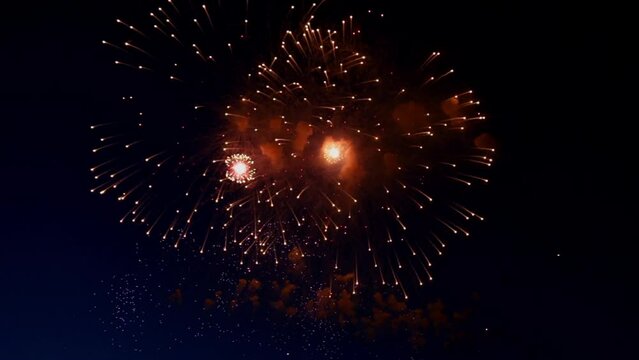 Fireworks of red color with a bright center explodes with bright sparks flying in all directions against a dark sky . High quality FullHD footage