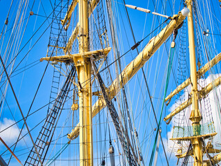 Vintage sailing ship mast ropes and tackle, Tall ship rigging mast detail, blue sky background