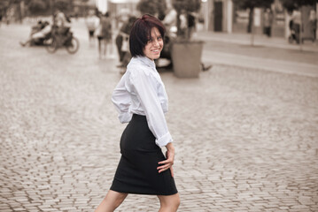 A teenage girl with a cheerful mood walks around the city and dances freely in the city center without looking at people, the girl is happy to start studying at college