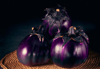 Several roound eggplants on a dark background