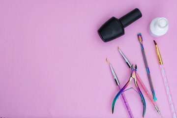 basic elements for a manicure, placed on a pink background. black and white nail polish, colored brushes, cuticle pusher and cuticle nippers items for sale and marketing in the aesthetic beauty market - obrazy, fototapety, plakaty