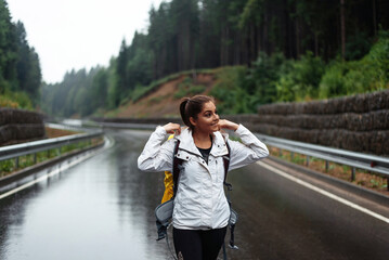 Hiker young woman looking away while walking with yellow backpack in nature outdoors