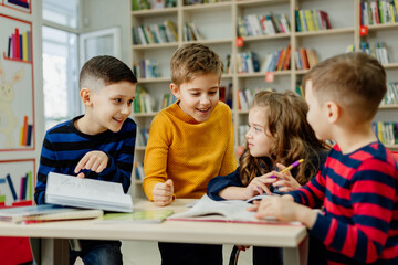 school children in the library reading books, doing homework, prepare a school project for lessons