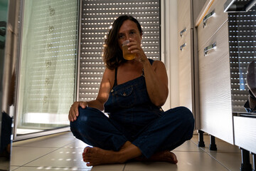 image of a beautiful middle aged woman drinking a cocktail sitting in her apartment