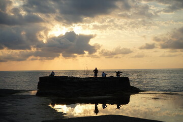 Angler vor dem Sonnenuntergang am Rosa Felsen an der Schwarzmeerküste mit dramatischen Wolken in...