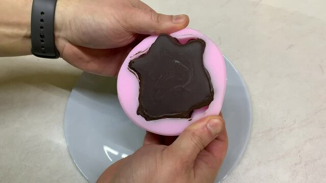 Man Hands Take Out Chocolate flower From Silicone Mold. Tasty dark chocolte anemon flower. Home confectionery.