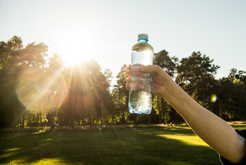 Bottle of clean drinking water in hand. Against the backdrop of a forest landscape