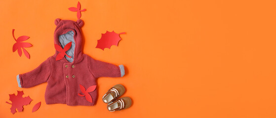 Stylish autumn baby clothes on orange background with space for text, top view