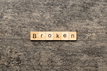 BROKEN word written on wood block. BROKEN text on cement table for your desing, concept