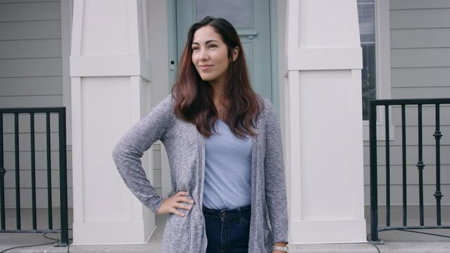 Confident Woman With Hand On Hip Stands In Front Of House Looking Around