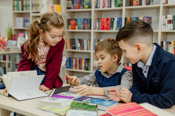 school children in the library reading books, doing homework, prepare a school project for lessons