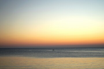 Sonnenuntergang mit einsamem Fischerboot auf dem Meer ins Licht der untergehenden Sonne in der...