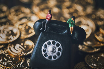 黒電話に座るミニチュアの男女