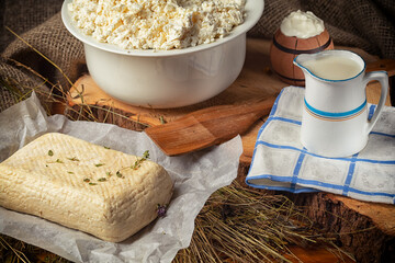 homemade wheel of cheese ang pitcher of milk on wooden table.