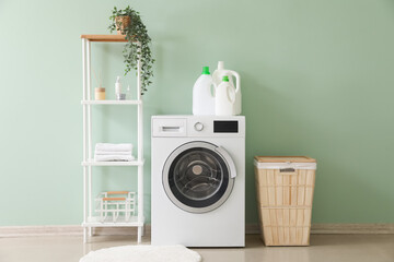 Interior of stylish laundry room with washing machine, shelving unit and basket - obrazy, fototapety, plakaty