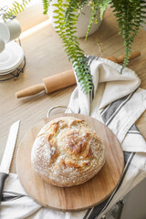 Cutting board with fresh bread, knife and napkin on counter in kitchen