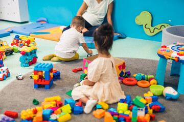 Creative playtime at nursery school. Toddlers playing with plastic building blocks, colorful cars...