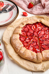 Sweet strawberry galette on light wooden table, closeup