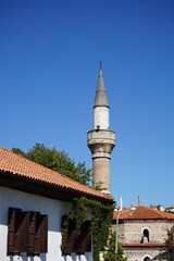 Minarett einer Moschee vor blauem Himmel im Sonnenschein in den Gassen der Altstadt von Safranbolu...