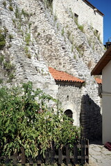 Felsgestein und altes Mauerwerk aus Bruchstein und Naturstein im Sommer bei blauem Himmel und...