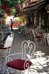 Weiße Stühle mit roten Kissen vor Cafés und Bistros im Sommer in den Gassen der Altstadt von...