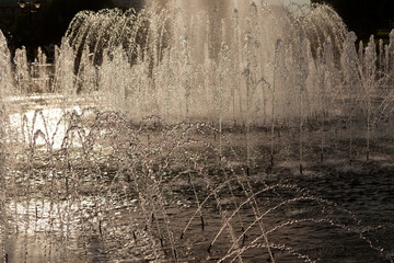 Fragment of fountain at sunset in sepia colors. Beautiful silvery streams of water sparkle in the...