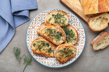 Plate of toasts with garlic and dill on grunge background