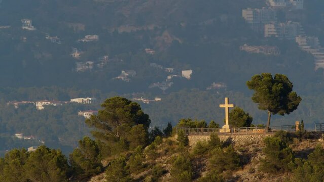 Scene of mountain town with Christian cross on the hill in La Nucia, Spain