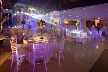 table set in night party hall with scenic lights, party room, birthday party, wedding party, party room,  party reception hall, sophisticated event,festive banquet room, ambient lighting