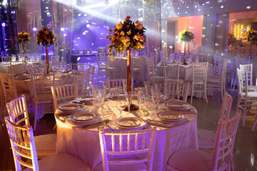 table set in night party hall with scenic lights, ornamental flowers, party room, new year party, new year, party hall, assembly room, birthday party