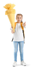 Obraz premium Happy young schoolgirl with backpack holding large yellow schultüte and giving thumbs up gesture for first day of school
