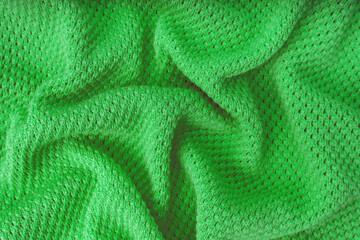 Close up background of knitted wool fabric with dots pattern. Bright green color crumpled knitting wool knitwear texture. Openwork abstract knitted jersey fabric abstract backdrop