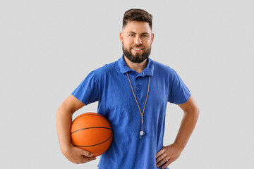 Handsome PE teacher with ball on light background