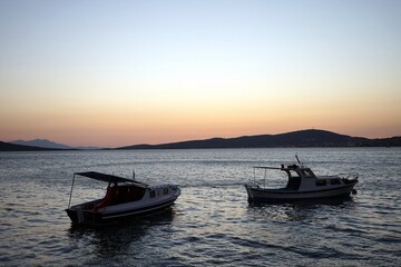 Romantische Abendstimmung mit dem Licht der Abendsonne am Hafen in der Bucht von Ayvalik mit Booten am Ägäischen Meer in der Provinz Balikesir in der Türkei