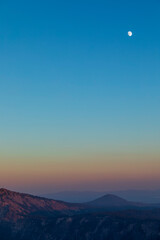 dramatic sunset sky on Crater Lake National park in Oregon with silhouette of surrounding mountain peaks on the background.