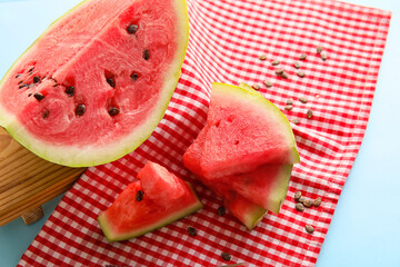 Slices of watermelon, seeds and napkin on blue background