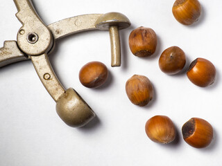Old nut cracker. Hazelnuts on a white background. Nuts in a shell. Snack. Healthy diet. Ingredients for preparing a healthy lunch. Broken hazelnut.