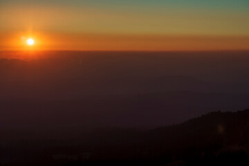 dramatic sunset sky on Crater Lake National park in Oregon with silhouette of surrounding mountain peaks on the background.
