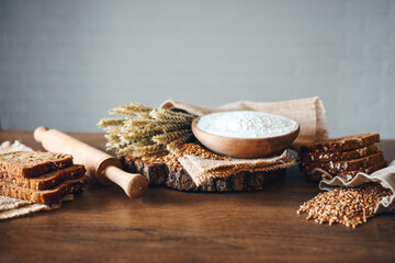 Bread, grains, ears of wheat and flour on a wooden background, bakery advertising banner