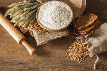 Bread, grains, ears of wheat and flour on a wooden background, bakery advertising banner