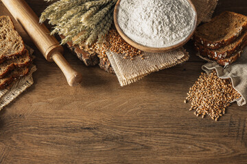Bread, grains, ears of wheat and flour on a wooden background, bakery advertising banner