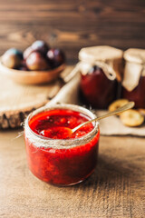 Glass jar with delicious homemade plum jam on table
