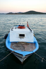Kleines Fischerboot in Blau und weiß vor klarem Himmel im Licht der Abendsonne im Hafen von Cunda...