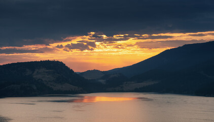 Dramatic Cloudy Sunrise in the desert landscape with mountains by the lake. Vernon, Okanagan, British Columbia, Canada. Canadian Nature Background.