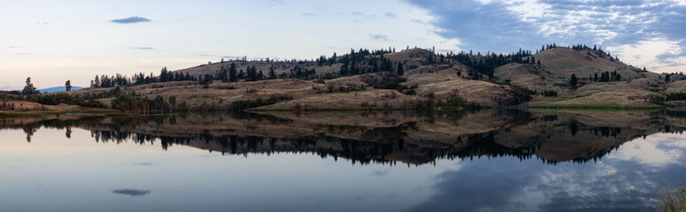 Panoramic View of a small lake in Canadian Landscape. Near Vernon, Okanagan, British Columbia, Canada. Nature Background Panorama. Colorful Sunrise Sky