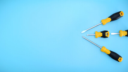 different type of yellow and black screwdrivers hand tools flat lay isolated baby blue background with copy space 